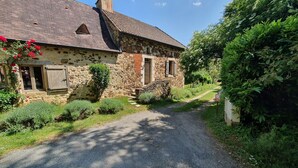 A stone house with a gravel driveway, surrounded by greenery. - House (ST MARTIAL DE NABIRAT)