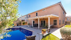 A two-story house with a covered patio, a swimming pool, and a well-maintained lawn.