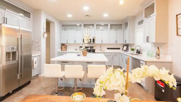 A modern kitchen with white cabinets, stainless steel appliances, and a central island with bar stools.
