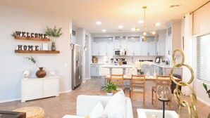 A modern kitchen with white cabinets, a central island, and pendant lighting.
