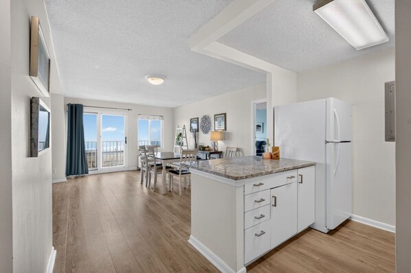 A modern kitchen with a central island, white cabinetry, and a large refrigerator.