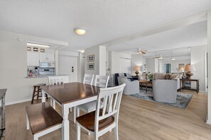 A modern kitchen with white cabinetry, a dining table with chairs, and a living area with a sofa and a coffee table.