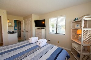 Enjoy a comfortable stay in this well-appointed room featuring a neatly made bed, TV, kitchenette, and storage unit.