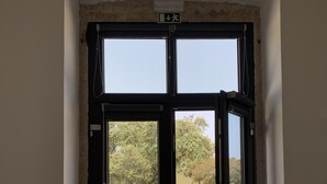 A doorway with a view of a paved area and trees. - Old Railway Station in Evoramonte - House #1 (Evoramonte)
