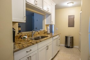 Kitchen features a granite countertop, stainless steel sink, and white cabinets with silver handles.
