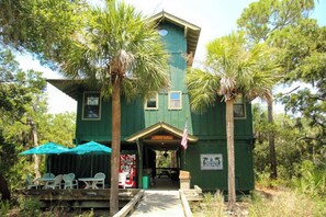 Situated in a wooded area, this cabin features a front porch with a bench and table.