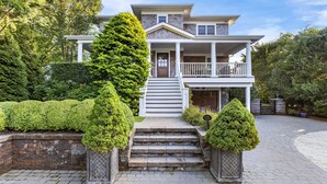 A two-story house with a front porch, steps leading to the entrance, and a driveway. - Beautiful Southampton Home with breathtaking waterfront views, front porch,... (Southampton)