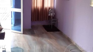 Ein Zimmer mit Glastisch, violetten Wänden, einem mit Vorhängen versehenen Fenster und einer Tür zu einem anderen Raum.