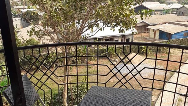Ein Balkon mit Metallgeländer, zwei quadratische Tische und vier Stühle.
