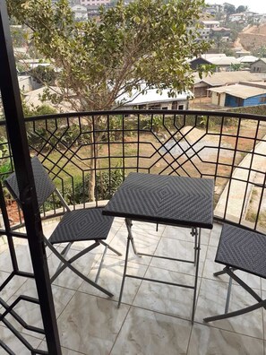 A balcony with a metal railing, two square tables, and four chairs. - Quiet, safe apartment with a view of greenery (Yaoundé)