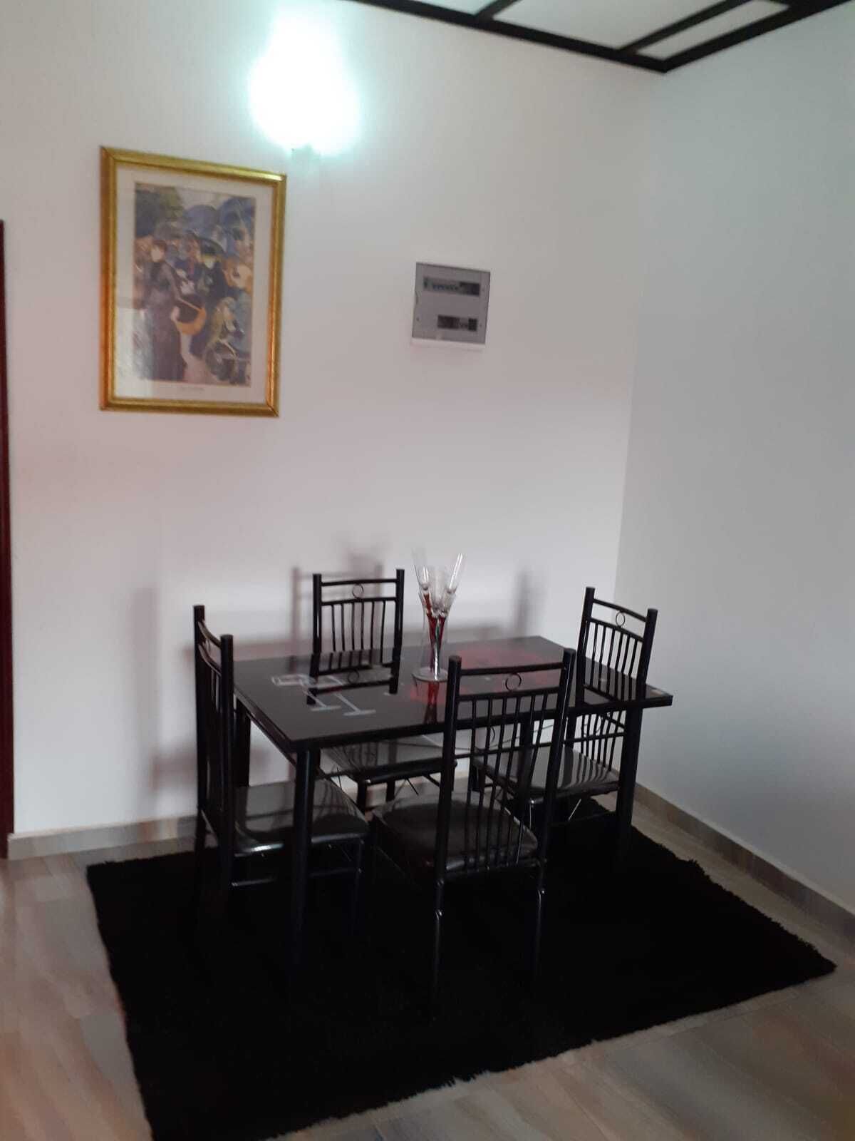 Ein Essbereich mit Tisch und Stühlen, einem gerahmten Bild an der Wand und einem Thermostat.
