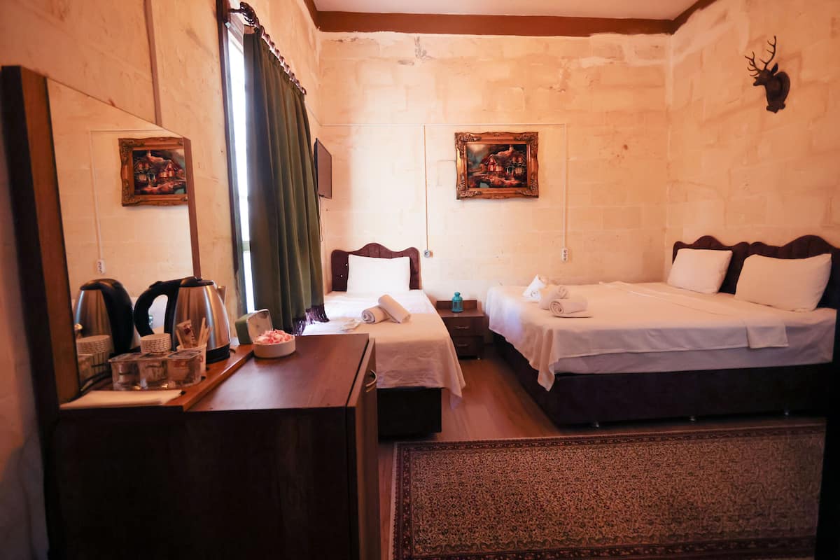A hotel room with two beds, a wooden desk, a mirror, and two framed pictures on the walls.