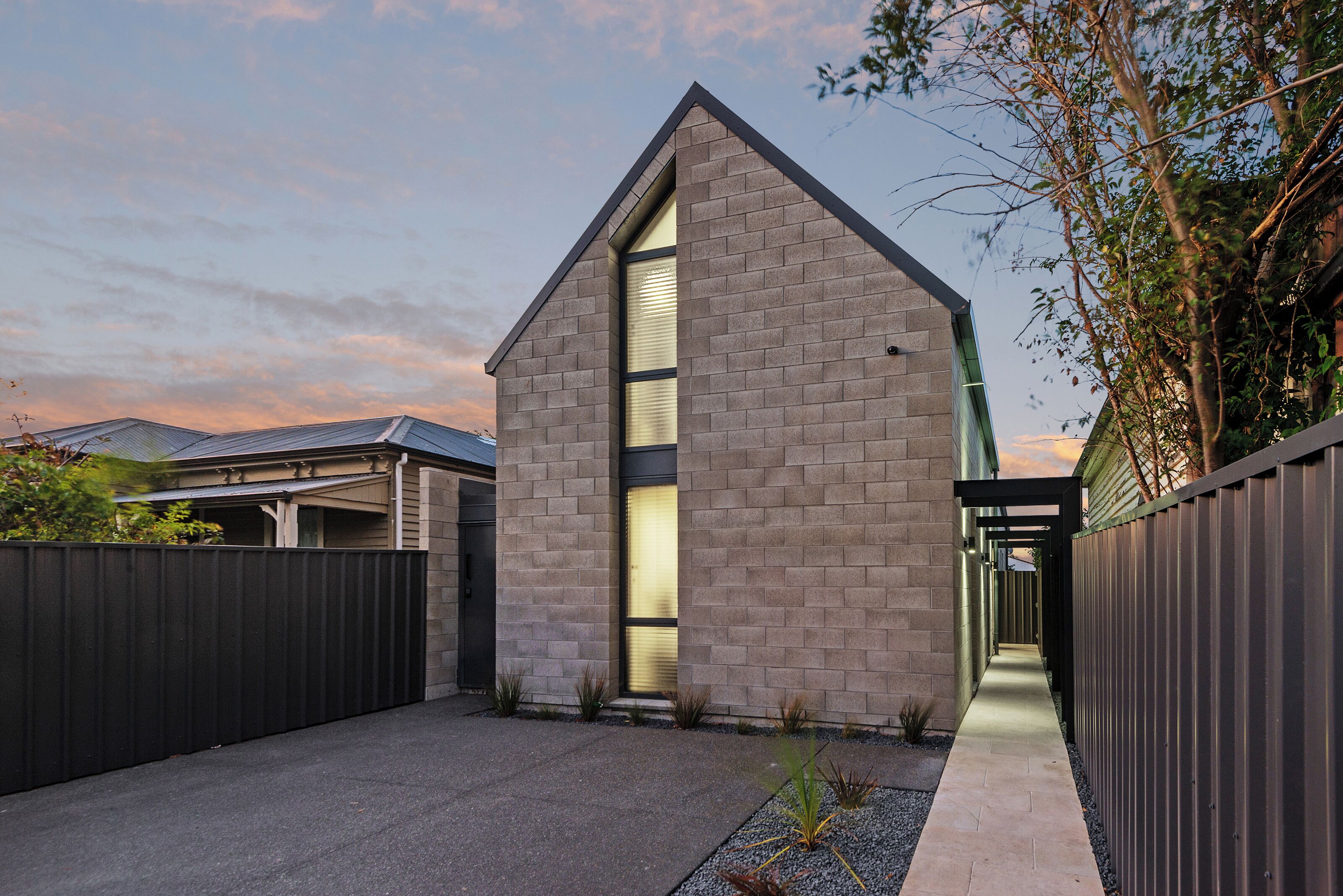 A modern house with a prominent brick facade, a large window, and a well-maintained garden area.