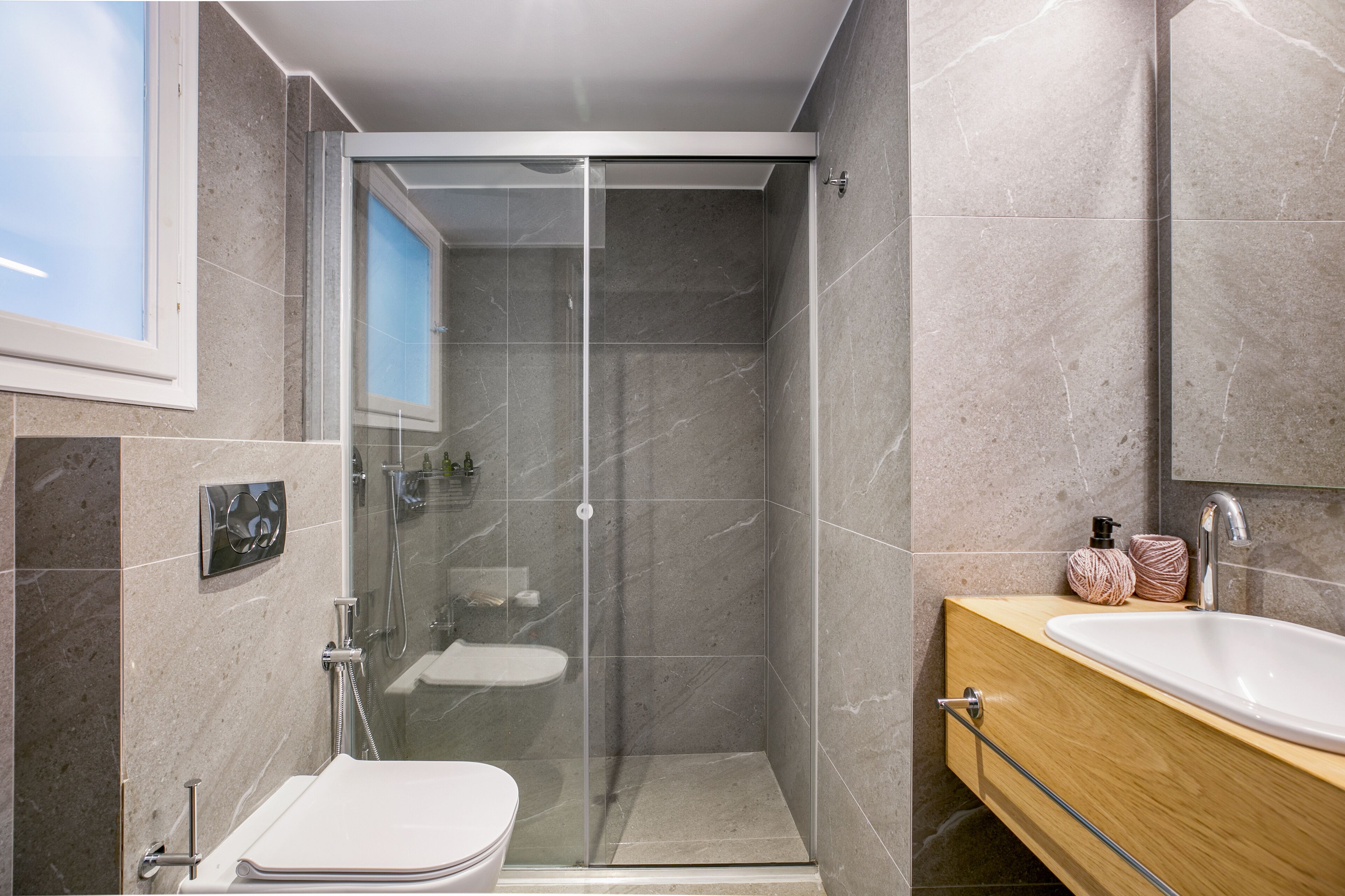 A modern bathroom with a glass-enclosed shower, a wooden vanity, and a white sink.