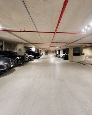 A multi-level parking garage with concrete floors and red structural beams.