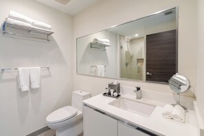 A modern bathroom with a toilet, sink, mirror, and towel rack.