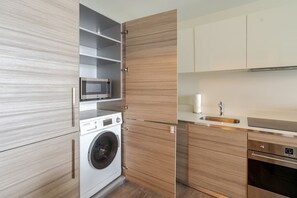 A compact kitchen with a built-in washer, microwave, and oven.