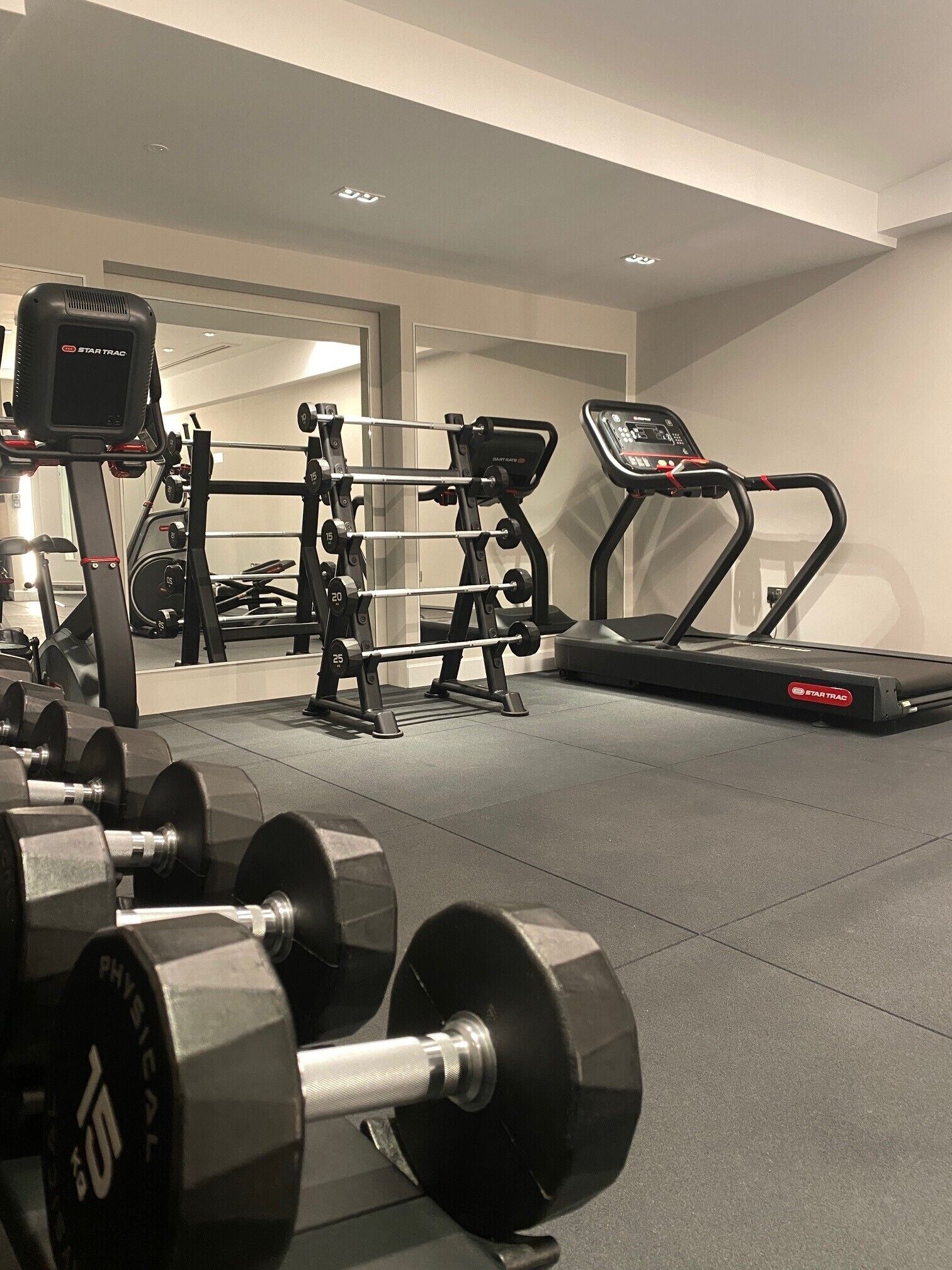 A gym with dumbbells, a treadmill, and weightlifting equipment.