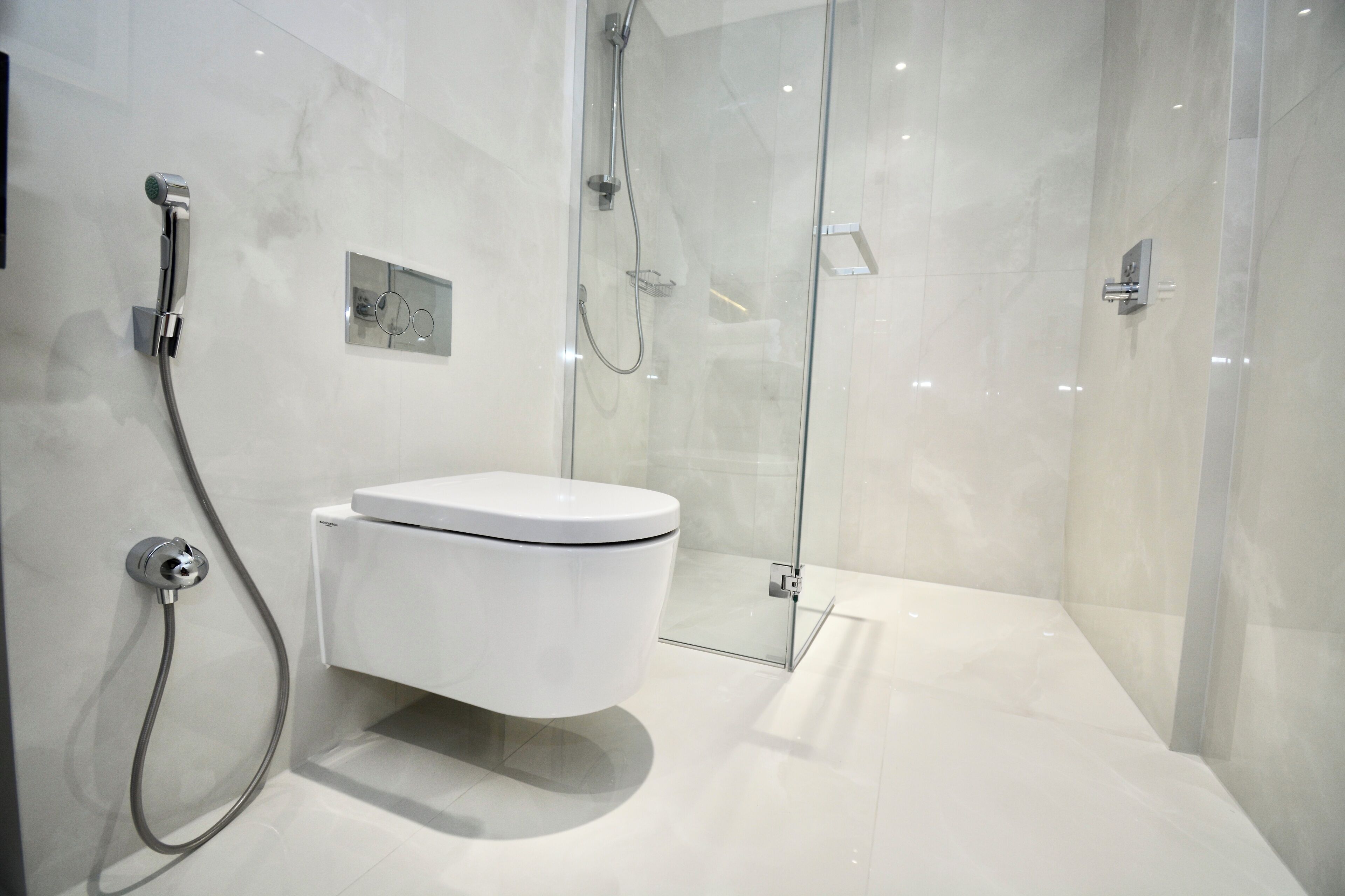 Une salle de bain moderne dotée d’une douche à parois de verre, de toilettes blanches et d’un design épuré.
