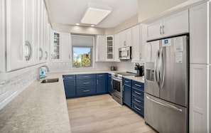 Enjoy cooking in this modern kitchen with a stainless steel refrigerator, oven, and sink, plus ample storage and a window for a view.