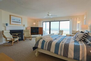 Een hotelkamer met een bed, een televisie, een open haard, een balkon met uitzicht en een plafondventilator.