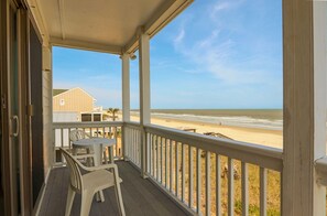 Een houten balkon met uitzicht op strand en zee.