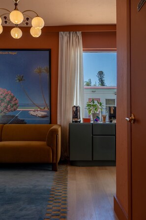 Una habitación con sofá, un cuadro, un escritorio con planta y vistas por la ventana.