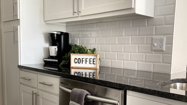 Una cucina moderna con mobili bianchi, un piano di lavoro nero e una macchina per il caffè.