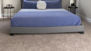 Una camera da letto con un letto, una ventola a soffitto, una finestra con persiane, un comodino e uno specchio.