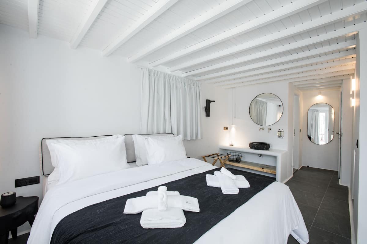 Une chambre d’hôtel avec un lit, une table de chevet, une coiffeuse avec un miroir et une porte de salle de bain.