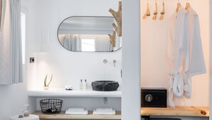 Un baño moderno con tocador blanco, espejo redondo, lavabo de mármol negro y toallero de madera.