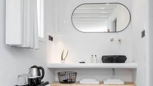 Un baño moderno con tocador blanco, lavamanos de mármol negro, una planta en maceta y un espejo.