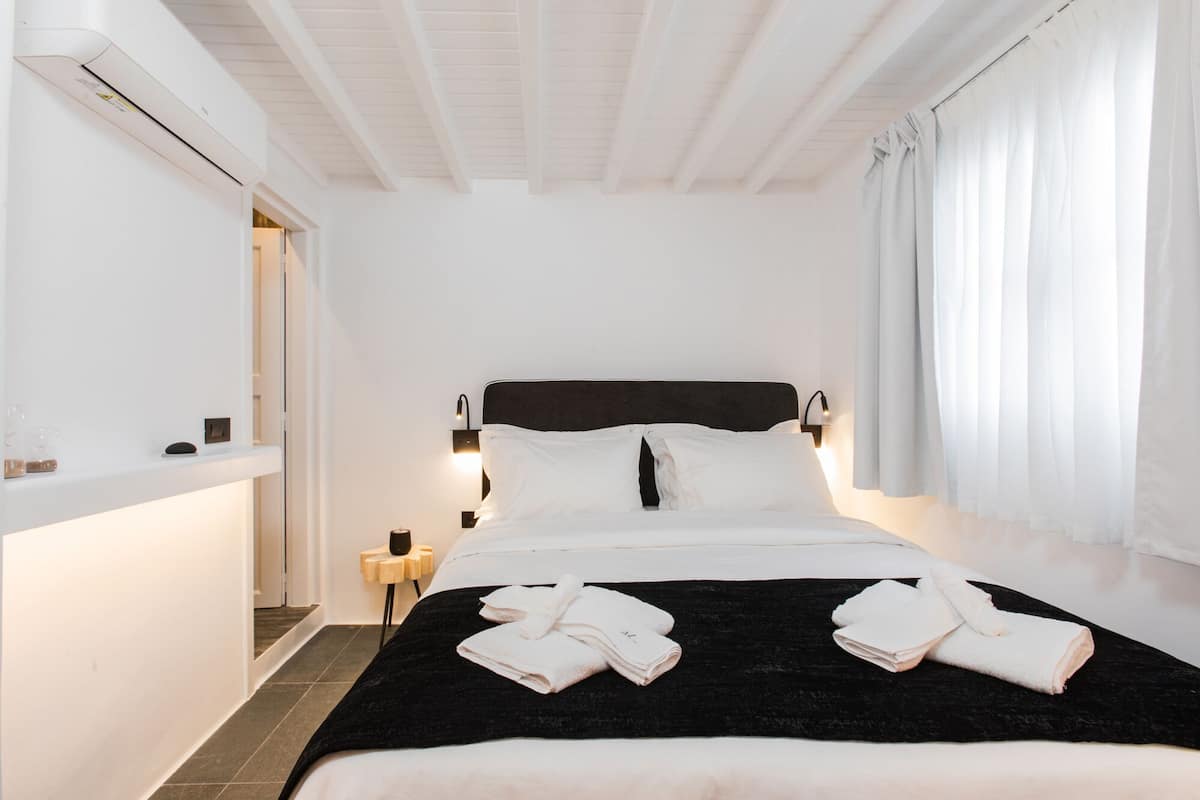 Une chambre d’hôtel équipée d’un lit, d’une table de chevet, d’une petite table et d’un climatiseur fixé au mur.