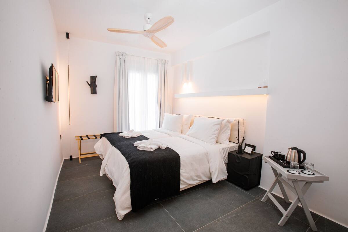 Une chambre d’hôtel moderne équipée d’un lit, d’une table de chevet et d’un ventilateur de plafond.