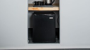 Una cocina con refrigerador integrado, cafetera y dos tazas en un estante.