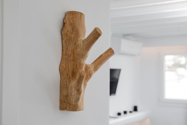 A wooden wall art piece in a room with a white wall, a window, and a flat-screen TV. - She Mykonos- Luxury Apartments (Mykonos)