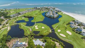 Ein Luftbild eines Golfplatzes mit Wasserhindernissen, einer Brücke und einem Strand.