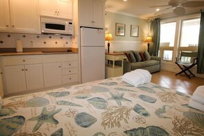 Enjoy a cozy stay in this nautical-themed room featuring a kitchenette, dining area, and seating space with large windows.