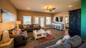 A spacious living room with a ceiling fan, a sofa, a coffee table, and a TV. - Amazing bay views from this 4 bedroom 4 bath house (Port Aransas)