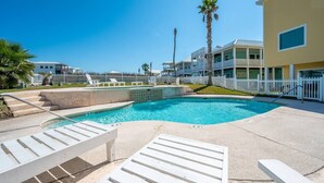A swimming pool with steps leading into it, surrounded by white lounge chairs and a white fence. - Amazing bay views from this 4 bedroom 4 bath house (Port Aransas)