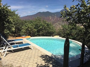 A swimming pool with lounge chairs and a view of mountains.