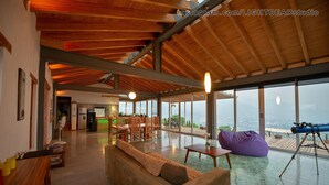 A spacious living area with a wooden ceiling, a sofa, a bean bag, a telescope, and a view of the outdoors. - Casa Utopia (Casa Divina + Horizonte): Divine house in nature close to the city (Oaxaca de Juarez)