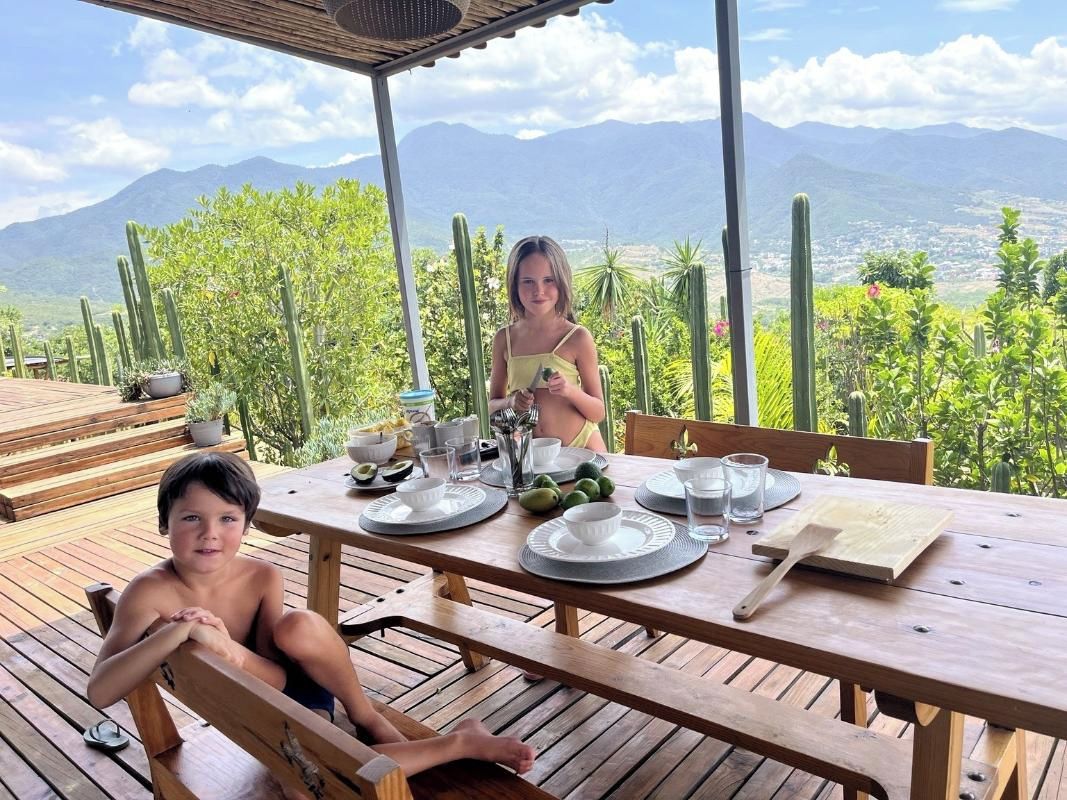 A wooden table set outdoors with a view of mountains and cacti.