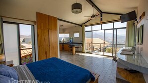 A modern bedroom with a large bed, a desk, and a balcony with a view of the mountains. - A beautiful loft in nature but close to the city, with pool /streamer (Oaxaca de Juarez)