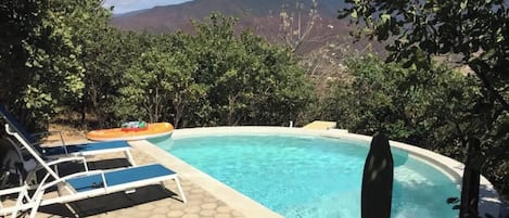 A swimming pool with lounge chairs and a view of mountains.