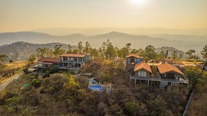 A residential area with houses featuring large windows and balconies, surrounded by trees and hills. - A beautiful loft in nature but close to the city, with pool /streamer (Oaxaca de Juarez)