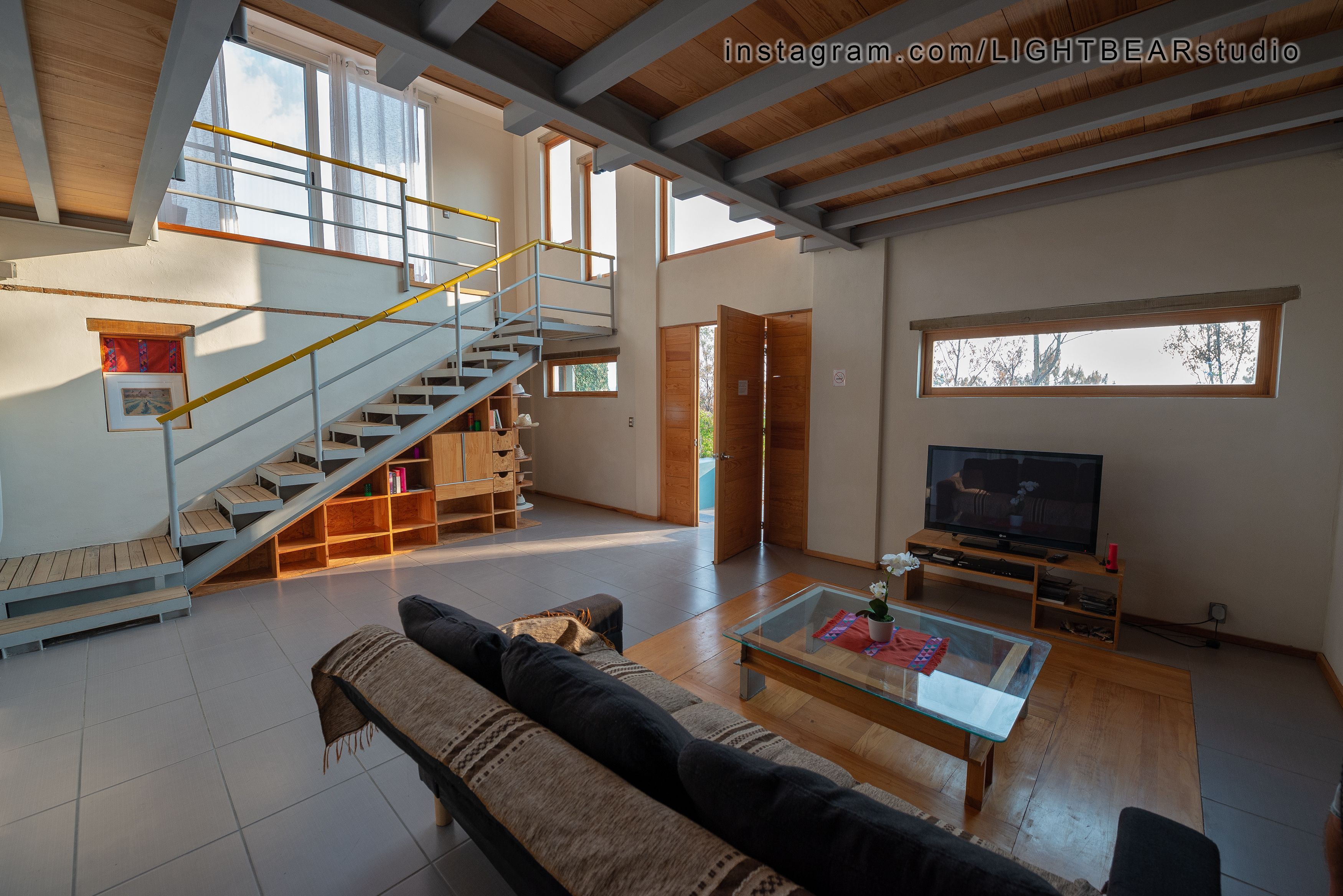 A spacious living area with a staircase, a sofa, a coffee table, and a television.