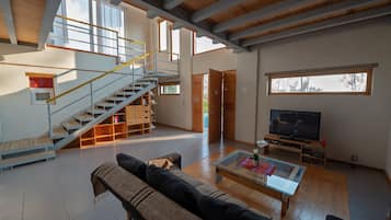 A spacious living area with a staircase, a sofa, a coffee table, and a television.