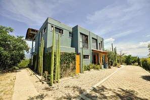 A modern two-story building with a flat roof, large windows, and a paved driveway. - Utopia Casa Horizonte: a house with a view, and all you need.   (Oaxaca de Juarez)