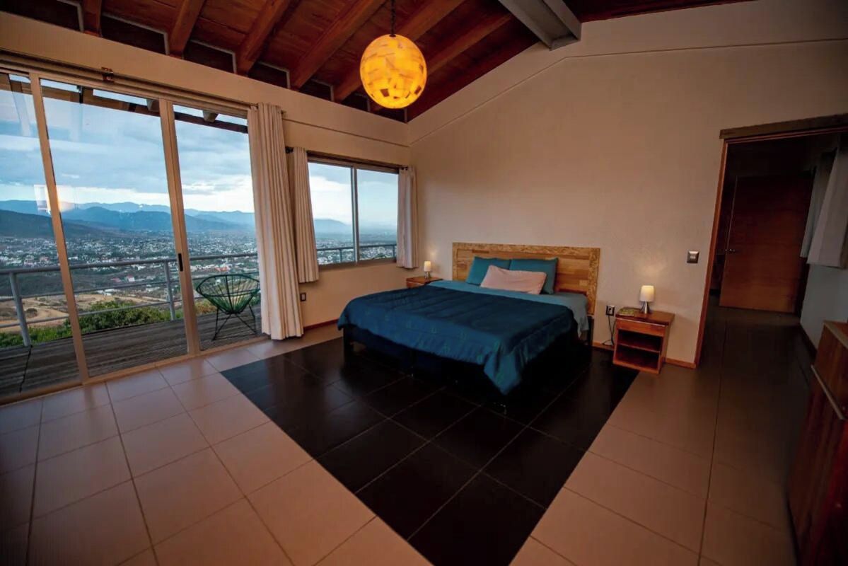 Un dormitorio con una cama grande, vistas a la ciudad y un balcón.
